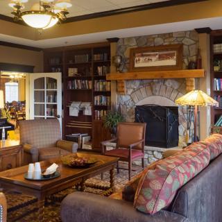 A cozy traditional living room with a stone fireplace and wooden bookshelves.