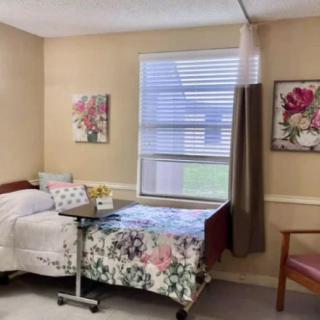 A hospital room with a bed, window, and floral decorations.