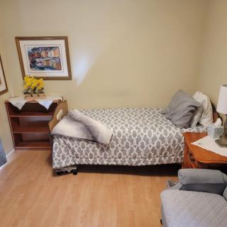 A cozy bedroom with a single bed, decorated with wall art and a small table lamp.