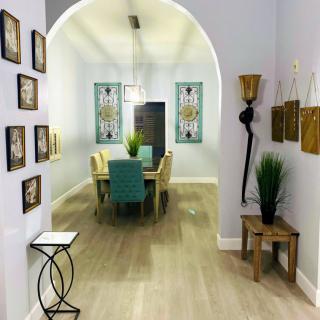 A modern dining room with stylish decor, featuring an archway, wooden flooring, and vibrant wall art.