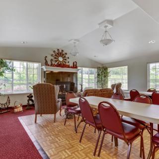 A spacious living room with red chairs and tables, featuring large windows and decorative elements on the walls.