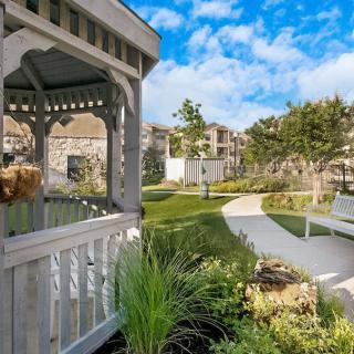 A serene garden scene featuring a gazebo and a winding pathway under a bright blue sky.