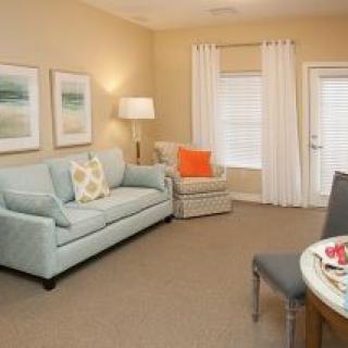 A cozy living room with a light blue sofa and matching chair, accented by warm lighting and modern decor.