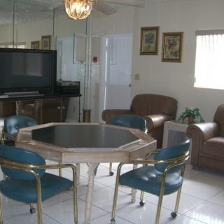 A cozy living room with a dining table and chairs, adjacent to a seating area with a television.