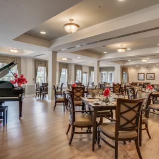 An elegant dining area featuring neatly arranged tables and a grand piano.