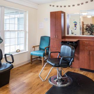 A cozy hair salon featuring stylish seating and a well-organized layout.