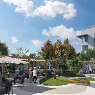 A lively outdoor patio scene with people enjoying the sunshine among trees and garden furniture.