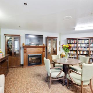 A cozy library room with a fireplace, bookshelves, and seating area.