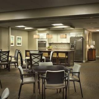 A modern kitchen and dining area with tables and chairs, featuring contemporary lighting and appliances.