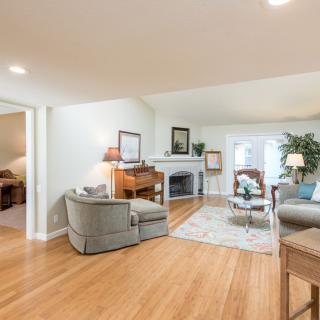 A spacious and well-lit living room featuring a comfortable sofa set, a fireplace, and polished hardwood floors.