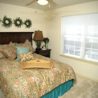 A cozy and stylish bedroom featuring a floral-patterned bedspread, soft lighting, and warm decor.