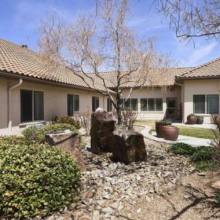 A serene courtyard with a tree and stone landscaping in front of a house.