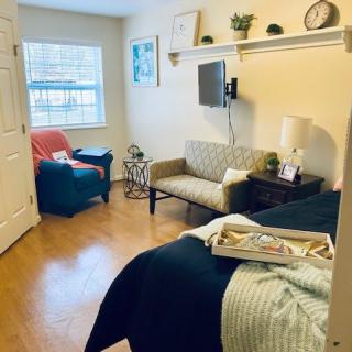 A cozy bedroom with a small sofa, wall-mounted TV, and decorative elements.