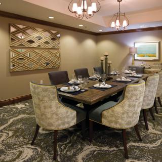 A well-decorated dining room with a large table, chairs, artwork on the wall, and elegant lighting.