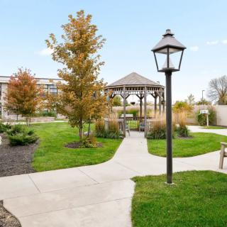 A scenic view of a park featuring a gazebo, pathways, and a lamp post amidst landscaped gardens.