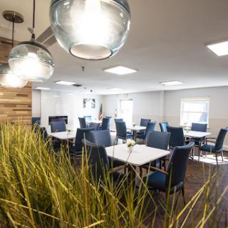 A modern dining area featuring stylish furniture, elegant lighting, and touches of greenery.