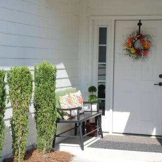 A welcoming front porch with a bench, plants, and a decorative wreath on the door.