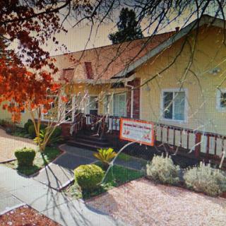 A charming yellow residential building with a welcoming porch and well-maintained landscaping.