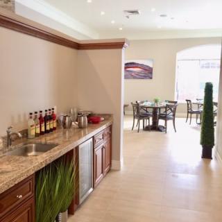 A modern kitchen and dining area with a sleek countertop, bar setup, and wooden cabinets.