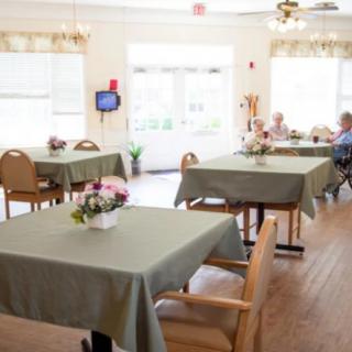 A bright and welcoming dining area with neatly arranged tables, adorned with floral centerpieces.