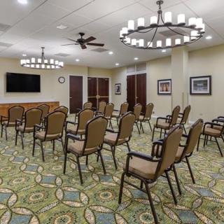 An empty conference room with arranged chairs, chandeliers, and a television.