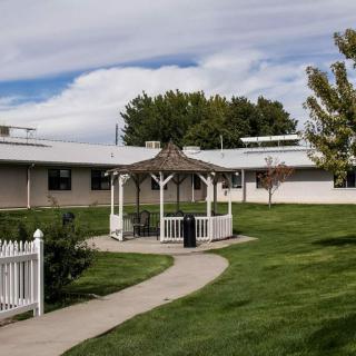 A serene outdoor setting with a pathway leading to a gazebo, surrounded by green grass and trees.