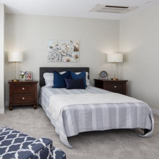 A well-decorated bedroom with a central bed, two nightstands, and stylish lamps.