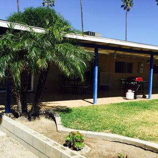 A house with a covered porch and palm trees on a sunny day.