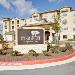 The image shows the exterior of a residential apartment complex with a prominent sign that reads 'Ledgestone Independent Living'.