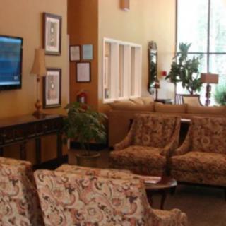 A cozy lobby area with sofas, a television, and plants.