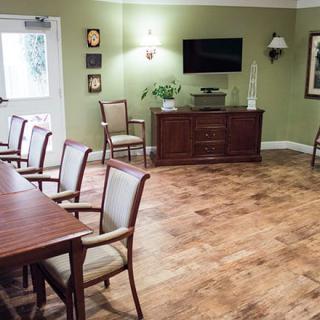 A well-lit conference room with chairs arranged along a table, featuring a television and wooden flooring.