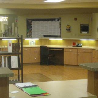 An empty office workspace with a desk, chair, and cabinets.