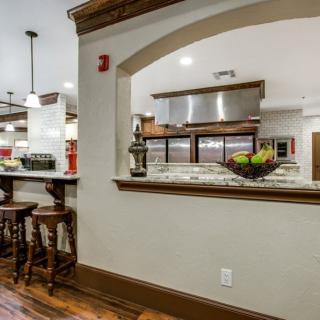 A modern kitchen with a large countertop, stylish stools, and wooden flooring.