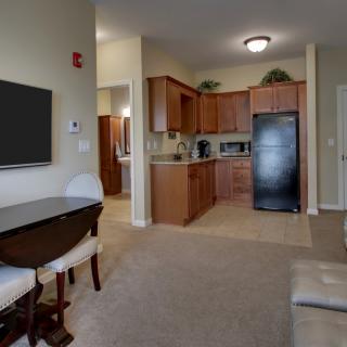 A cozy apartment interior featuring a living room with a television and dining area adjacent to a modern kitchen.
