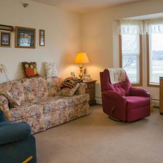 A cozy living room featuring a floral sofa, maroon armchair, and warm lighting.