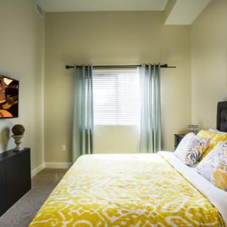 A modern bedroom with yellow bedding and natural light filtering through a window.
