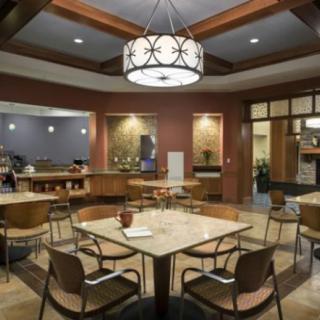 A modern cafe interior with a central table, stylish chandelier, and seating area.