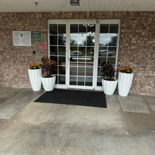 The entrance of a building adorned with stylish plant pots and a welcome mat.