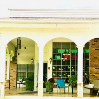 A building exterior featuring arches, columns, and a seating area.