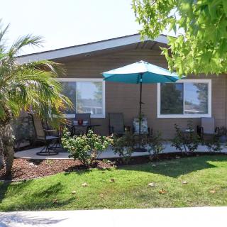A cozy house with a landscaped front yard featuring a patio with an umbrella.