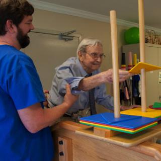 A caregiver assists an elderly person with a hands-on activity, promoting engagement and learning.