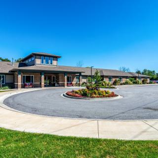 A modern building with a circular driveway under a clear blue sky.