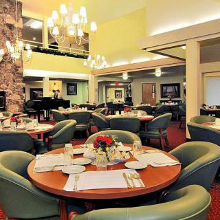 An elegant restaurant dining area with neatly arranged tables and chairs, illuminated by a chandelier.
