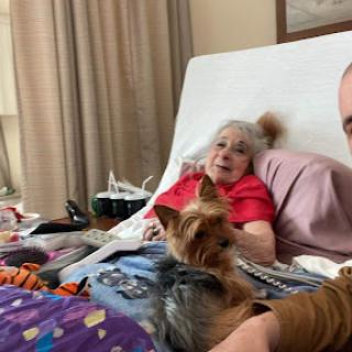 A heartfelt moment shared between a loved one and their furry companion in a cozy bedroom.