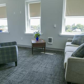 A cozy living room with a sofa, two chairs, and a coffee table near large windows.