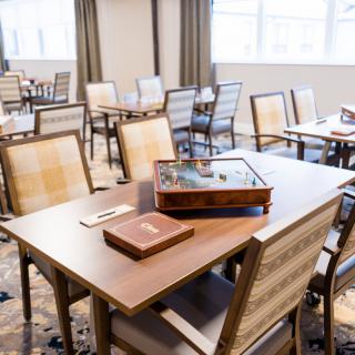 A neatly arranged dining room with wooden tables and chairs, featuring elegant place settings.