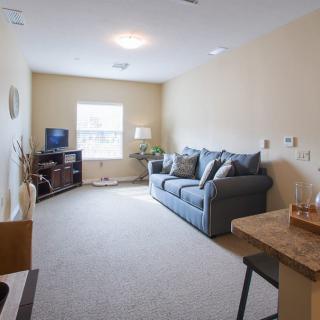 A cozy living room with a sofa, television, and natural light coming through a window.