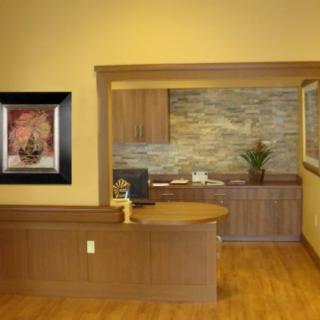 A well-organized office reception area with a wooden desk, artwork on the wall, and a stone accent backdrop.