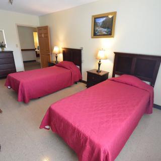 A hotel room with two twin beds and simple decor.