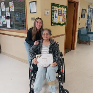A joyful moment shared between two individuals, one in a wheelchair holding a certificate.